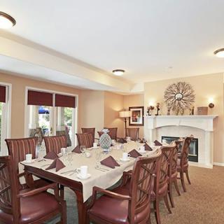 A cozy dining room with an elegant table setting, featuring a fireplace and large windows letting in natural light.