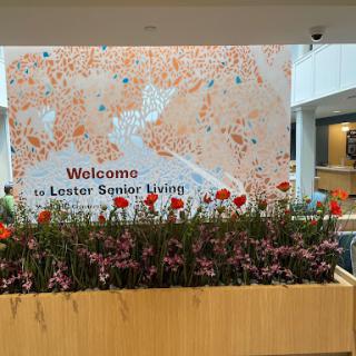A welcoming display at Lester Senior Living with vibrant flowers and a decorative wall.