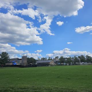 A serene view of a grassy field under a blue sky filled with fluffy clouds.