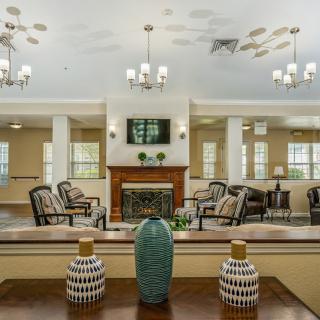 A spacious living room with a fireplace, chandeliers, and decorative vases.