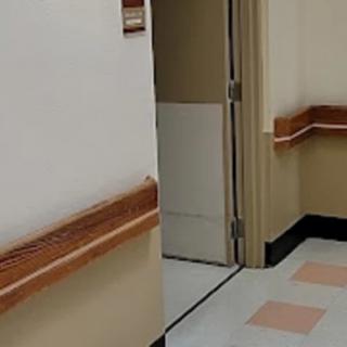 A view of a hospital hallway with an open door revealing part of the interior.