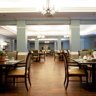 A spacious dining room with elegant chandeliers, neatly arranged tables, and a warm ambiance.
