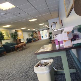 A spacious waiting area with comfortable seating, plants, and a table.