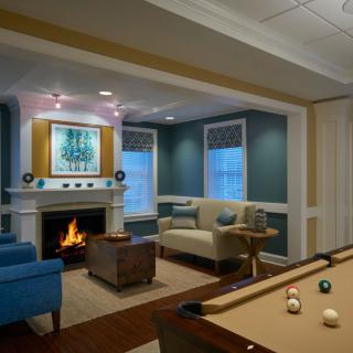 A cozy living and game room with a fireplace and billiards table, featuring modern interior design.