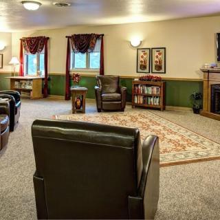 Cozy living room with armchairs, a fireplace, and bookshelves.