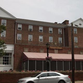 A brick hotel building with a covered entrance and parked car in front.