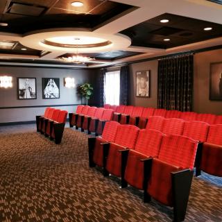 Luxurious theater with rows of red seating and elegant decor.