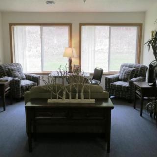 A cozy living room with comfortable chairs and a lamp by the windows.