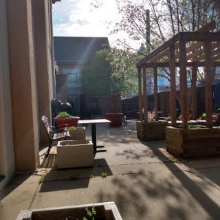 A serene outdoor courtyard basking in sunlight, featuring seating areas and greenery.
