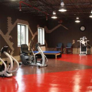 A spacious gym interior featuring exercise equipment and a vibrant red floor.