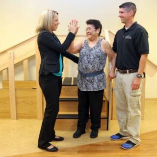 A physical therapy session with a patient supported by two therapists.
