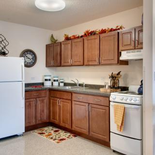 A cozy kitchen featuring wooden cabinets, a white refrigerator, and a compact stove.