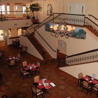 A spacious restaurant interior featuring a central staircase and elegantly set tables.