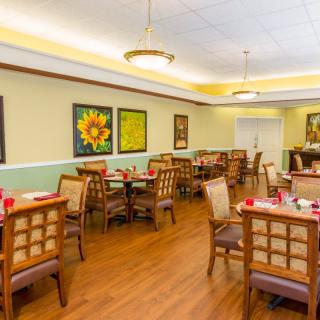 A cozy indoor dining area with tables and chairs arranged neatly, featuring colorful artwork on the walls.