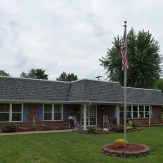 A welcoming residential building with a well-maintained lawn and an American flag.