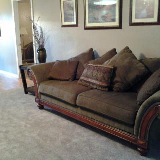 A cozy living room featuring a brown sofa with decorative cushions and framed artwork on the walls.