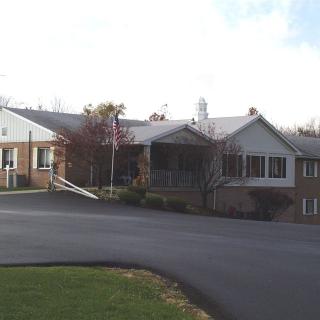 A suburban residential building with a paved driveway and surrounding greenery.