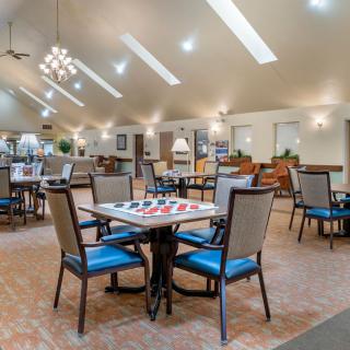 A spacious and well-lit dining area with multiple chairs and tables arranged for gatherings.