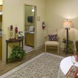 A cozy living room area with a decorative rug, a comfortable chair, and a lamp providing ambient lighting.
