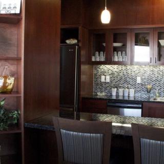 A modern kitchen with dark wood cabinets, a stylish backsplash, and pendant lighting.