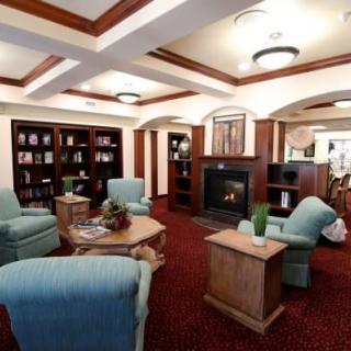 A cozy library reading room with armchairs, bookshelves, and a fireplace.