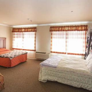 A spacious bedroom with two beds and large windows adorned with curtains.
