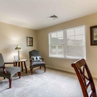 Cozy living room with chairs, a table, and a large window allowing natural light.