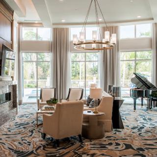 A beautifully designed lounge area featuring comfortable seating, a grand piano, and ample natural light.