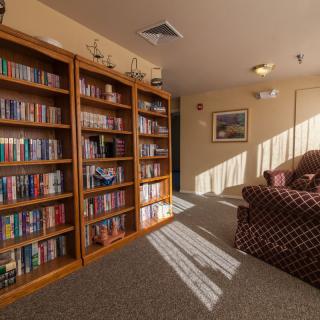 A cozy library corner with bookshelves filled with books and a comfortable sofa bathed in natural light.