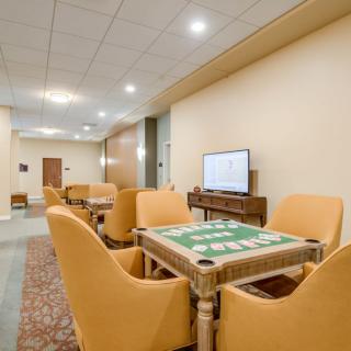 A cozy lounge area with comfortable chairs, a game table, and a television.