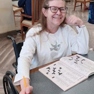 A joyful senior woman in a wheelchair enjoying a puzzle activity.