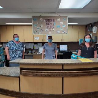 Healthcare staff standing at the hospital reception desk wearing masks.