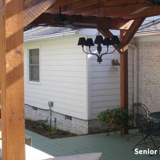 A cozy backyard patio with a wooden pergola and garden.