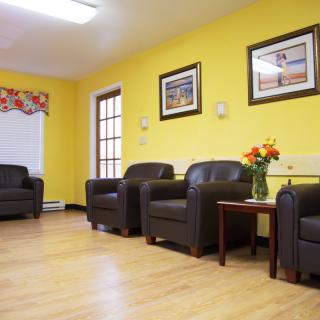 A comfortable waiting room with leather chairs, yellow walls, and decorative artwork.