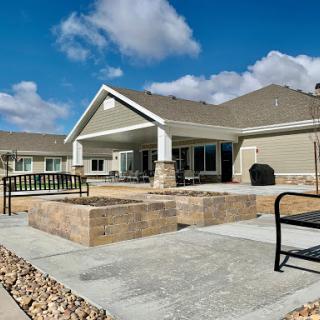 A modern house with a spacious patio area, surrounded by landscaped stone features and a clear blue sky.