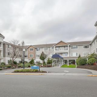A view of a residential apartment complex with landscaped surroundings under a cloudy sky.