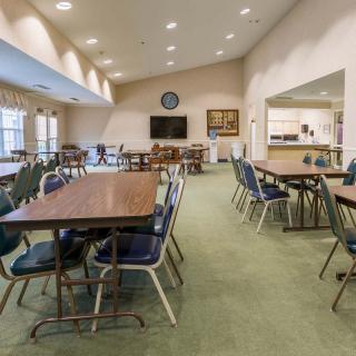 A spacious community room with multiple tables and chairs, suitable for meetings or gatherings.