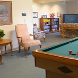 A cozy living room featuring a pool table, comfortable seating, and a television.
