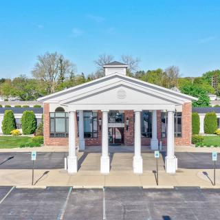 A building with a columned entrance and adjacent parking lot under a clear blue sky.