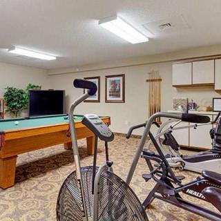 A recreation room featuring a stationary bike, fitness equipment, and a pool table.