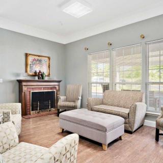 A cozy living room with a fireplace, comfortable seating, and large windows.