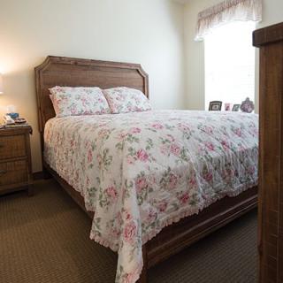 A cozy bedroom with a wooden bed frame and floral-patterned bedding.