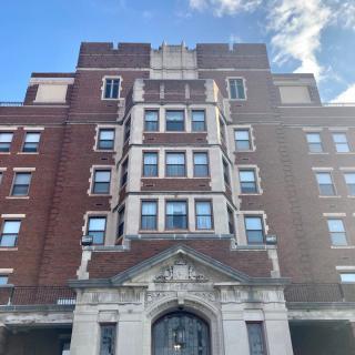 A historic brick building with multiple windows against a blue sky.