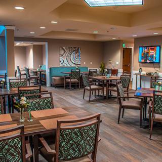 A modern and stylish restaurant dining area featuring neatly arranged tables and chairs, with elegant artwork adorning the walls.