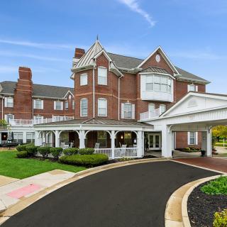 A classic brick hotel with a grand entrance and circular driveway set against a clear blue sky.