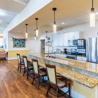 A modern kitchen with a large granite countertop and stylish pendant lighting.