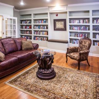 A cozy living room with built-in bookshelves, a leather sofa, and an elegant armchair.