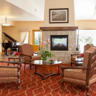 A cozy living room with a fireplace, comfortable seating, and a grand piano in the corner.