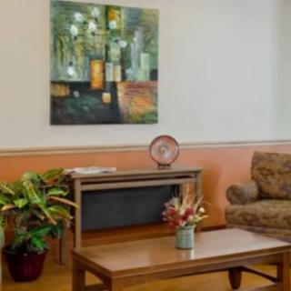 A cozy living room with a sofa, coffee table, plants, and an abstract painting on the wall.