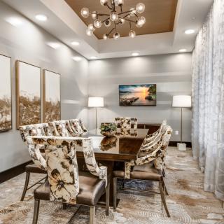 A modern dining room with a chandelier and decorative chairs, complemented by elegant artwork and soft lighting.